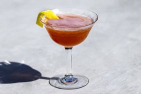 Allegheny Cocktail with lemon twist against a grey background