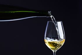 Bottle of white wine pouring into glass