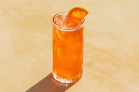 The Bicycle Thief cocktail in a highball glass with slice of grapefruit agains a cream colored background.