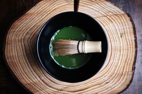 Green Tea Matcha in a bowl with a whisk, on a tree stump.