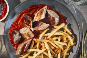 Currywurst and french fries on a grey plate shot from above.