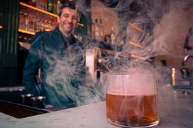 Bartender standing behind bar with cocktail on counter