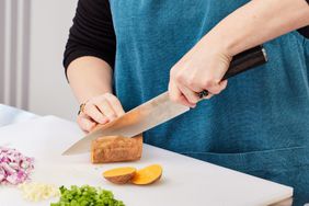 Hands slicing a sweet potato lengthwise with a Paudin Pro 8-Inch Chefâs Knife