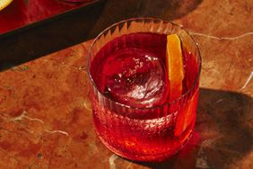 A non-alcoholic negroni with a slice of orange and a large ice cube.