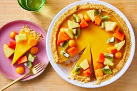 a bright orange pie with a crumb crust and chunks of tropical fruits in a ring around the top