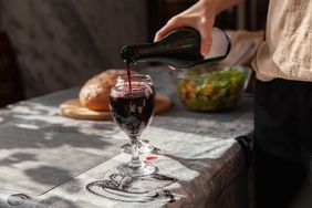 A person pouring wine into two glasses.