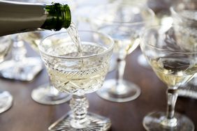 Sparkling wine being poured into coupe glasses.