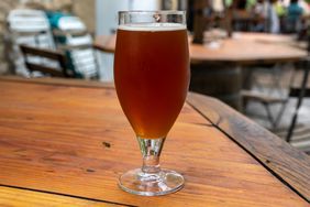 a beer on a table with other tables and chairs in the background