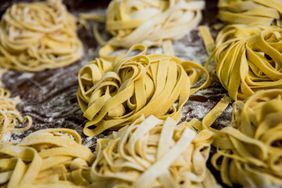 Homemade tagliatelle pasta on a floured table.