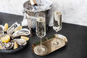 Champagne glasses with sparkling wine and bottle in bucket near oysters.